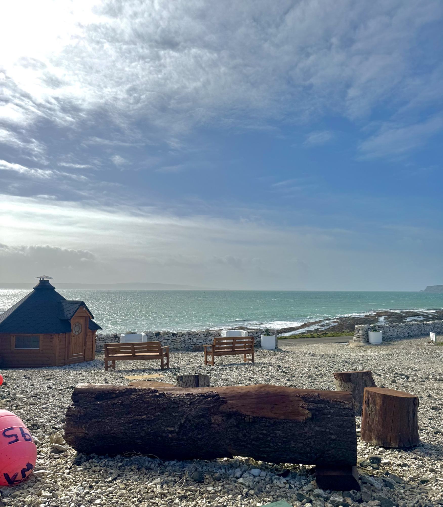 The timber barbeque hut and shore benches at Rathlin Glamping, looking out over a bright winter sea.